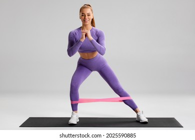 Fitness Woman Doing Exercise For Glutes With Resistance Band On Gray Background. Athletic Girl Working Out