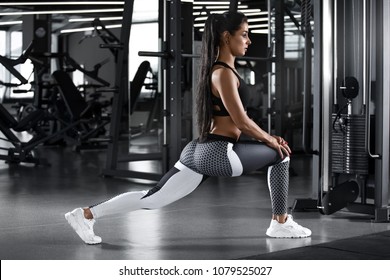 Fitness woman doing lunges exercises for leg muscle workout training in gym. Active girl doing front forward one leg step lunge exercise