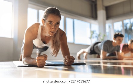 Fitness woman doing plank exercise workout in a group of people in gym. Sport girl and men in sportswear doing exercising on yoga mat, planking indoors - Shutterstock ID 2247653677