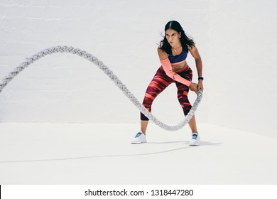 Fitness woman doing strength training using battle rope. Athletic woman doing workout with battle rope.