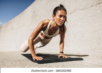 Fitness woman doing wide mountain climbers exercise. Female in sportswear exercising on fitness mat outdoors.