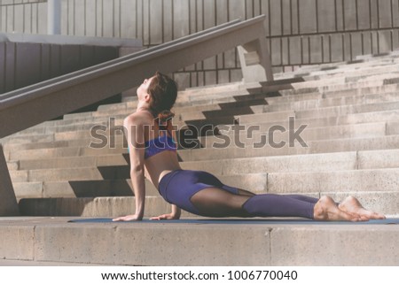 Fitness woman doing yoga urban practice outdoors. Healthy young girl practising yoga on seaside promenade