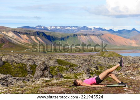 Fitness woman exercising single leg glute bridge exercise training butt and legs outside in beautiful nature landscape on Iceland. Fit female sports model working out.
