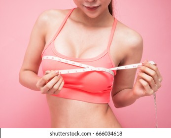 Fitness woman fit girl in sportswear with measure tape measuring her size chest breast on pink background