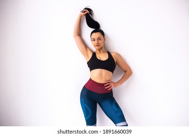 Fitness Woman Holdind Her Hair In Black T-shirt And Sports Leggings, Studio Shot.