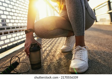 Fitness Woman Holding Bottle Of Water. Female Taking A Break From Workout Outside. Close Up.