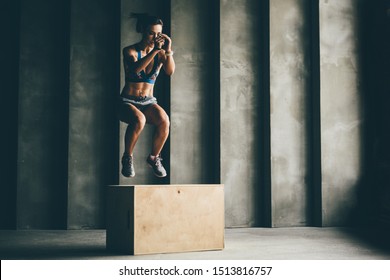 Fitness Woman Jumping On Box While Training At The Gym,girl Doing Cross Fit Exercise. Sports Concept, And Healthy Lifestyle.