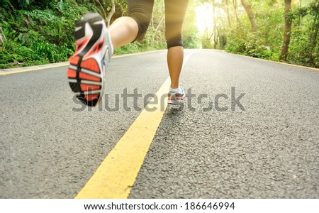 fitness woman legs running at forest