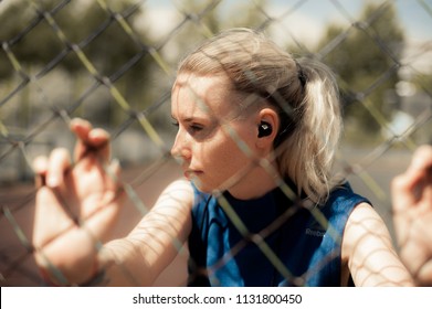 Fitness Woman Listening Music in Wireless Headphones, Doing Workout Exercises On Street. Beautiful Athletic Fit Girl Relaxing After Training. Sport style 