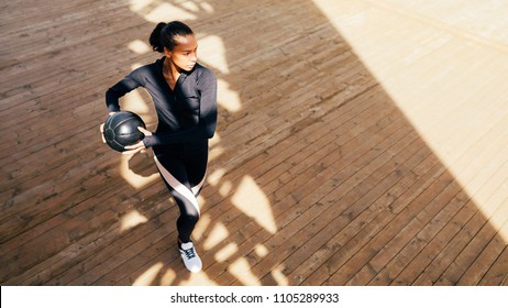 Fitness woman with medicine ball stretching and warming up outdoors 