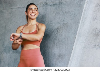 Fitness woman monitoring her heart rate with a smartwatch. Sports woman tracking her progress after a run. Happy woman doing a cardio workout outdoors. - Powered by Shutterstock