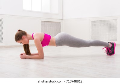 Fitness Woman Plank Workout Training At White Background Indoors. Young Slim Girl Makes Exercise.