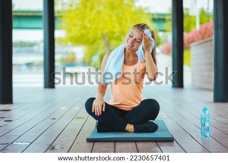 Fitness woman Relaxing after exercise with a whey protein bottle. Relaxing after training. Beautiful young woman looking away while resting after running. Proud woman after exercise 