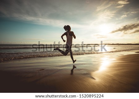 Fitness woman runner running on sunset beach