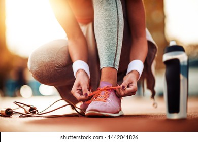 Fitness woman runner tying sport shoes before running. - Powered by Shutterstock
