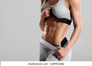 Fitness woman showing abs and flat belly, isolated. Athletic girl shaped abdominal