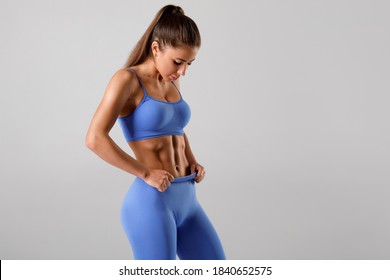 Fitness Woman Showing Abs And Flat Belly On Gray Background