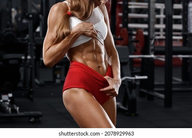 Fitness woman showing abs and flat belly in gym. Beautiful athletic girl, shaped abdominal