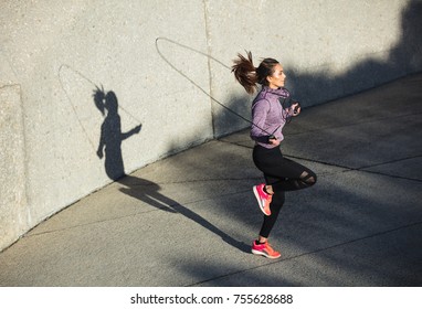 Fitness woman skipping with a jump rope outdoors. Female doing fitness training in morning. - Shutterstock ID 755628688