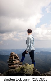 fitness woman standing on top of a mountain and enjoying stunning valley view