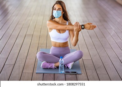 Fitness woman stretching outdoor with a face mask. One young woman doing stretching exercises and wearing a mask. Woman with a protective face mask stretching and exercising outdoors
