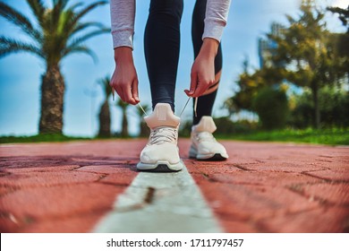 Fitness woman ties shoelaces on beige sneakers and get ready for morning jogging and sports workout outdoors. Do sport and be fit. Sports people with healthy sporty lifestyle     - Shutterstock ID 1711797457