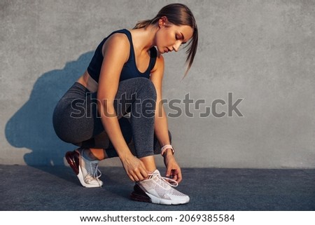 Fitness woman tying shoelaces before training, Cheerful runner sits on the floor in the street in sports shoes, Active woman tying lace shoes before jogging Foto stock © 