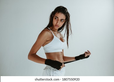 Fitness woman wearing hand wraps for workout. Fitness female getting ready for physical training against white background. - Powered by Shutterstock