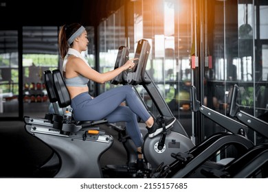 Fitness Woman Wearing Sportwear And Workout Headband On  In The Gym. Woman Is Setting Setup Machine Stationary Bike Screen Options At Gym.