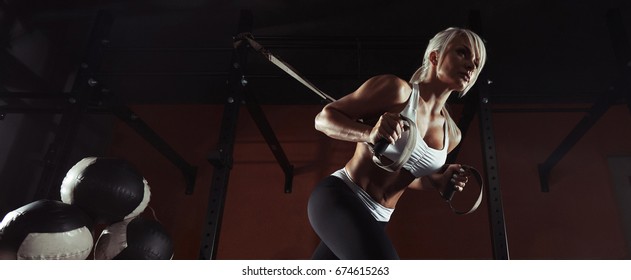 Fitness-Frau trainieren am TRX im Fitnessraum. Fitness-Frau trainiert am CrossFit. Fitness-Frau im Fitnessraum. Überlebende Frau. Crossfit-Stil. Training von TRX-Gurten. TRX Gymnastik