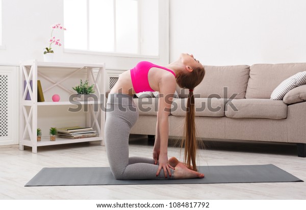 Fitness, woman yoga relax meditation in\
camel pose at home. Young slim girl makes\
exercise.