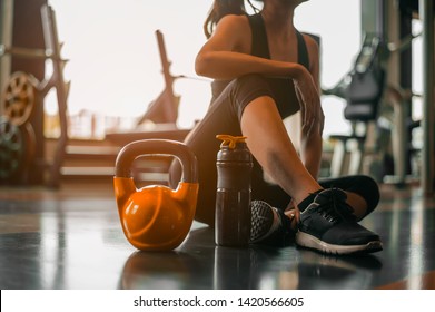 
fitness ,workout, gym exercise ,lifestyle  and healthy concept.Fitness woman Relaxing after exercise with a whey protein and dumbbell placed beside the gym.Relaxing after training.