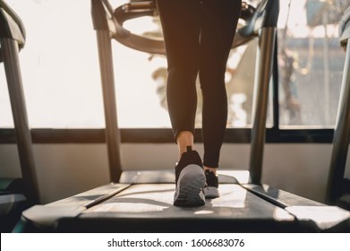 fitness, workout, gym exercise, lifestyle and healthy concept. Close-up Legs and feet of women walking on the treadmill in the gym for good health and strength at sunset.