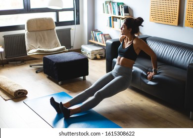 Fitness workout at home. Healthy fit young woman doing triceps dips exercise in the living room.