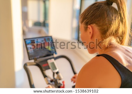 Fitness workout woman training at home on smart stationary bike equipment connected online live streaming class indoors for biking exercise. Indoor cycling. Focus on the sweat on person's back. Stock photo © 