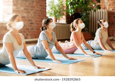 Fitness, Yoga And Healthy Lifestyle Concept - Group Of People In Medical Masks Doing Cobra Pose On Mats At Studio