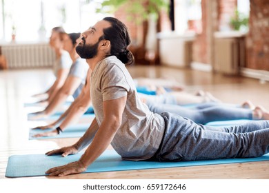 fitness, yoga and healthy lifestyle concept - group of people doing cobra pose on mats at studio - Powered by Shutterstock
