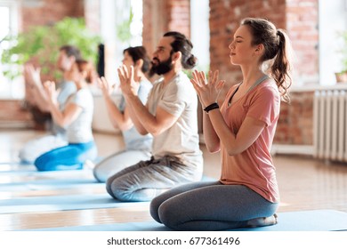 fitness, yoga and healthy lifestyle concept - group of people doing lotus seal gesture and meditating in seated pose at studio