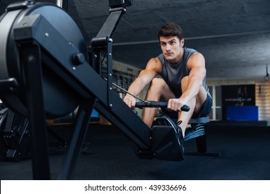 Fitness Young Man Using Rowing Machine In The Gym