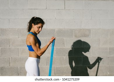 Fitness Young Woman Doing Biceps Curl With Resistance Band For Training Arms Strength. Female Athete Exercising Outside.