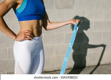 Fitness Young Woman Doing Biceps Curl With Resistance Band For Training Arms Strength. Female Athete Exercising Outside.