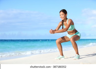 Fitness young woman working out core and glutes with bodyweight workout doing squat exercises on beach. Asian sporty girl squatting legs as part of an active and fit life.