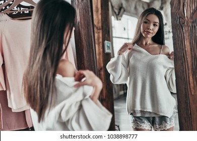 Fits Perfect. Attractive Young Woman Trying On The Blouse And Smiling While Standing In Front Of The Mirror At Home