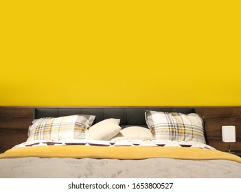 Fitted Bed With Pillows In The Bedroom On The Yellow Wall Background