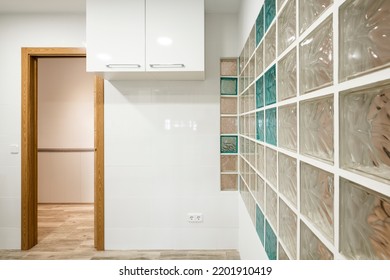 Fitted Kitchen With White Glossy Wood Cabinets And Skylight Wall With Glass Pavers