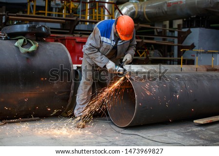 Fitter processes pipe edge with electric hand grinder