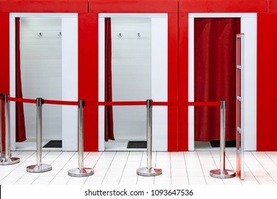 Fitting Rooms In The Supermarket. A Clothing Store With A Place For Fitting In The Mall. Anti-theft Gates. Ribbon Guard. Red Curtains. Tiled Floor. Hooks For Clothes And Rugs. Dressing Room Curtain.