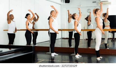 Five aduls people doing exercises on stretching ballet barre - Powered by Shutterstock