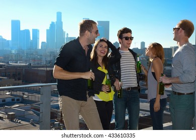 Five Adult Friends Flirting And Drinking Beer At Rooftop Bar With Los Angeles Skyline, USA