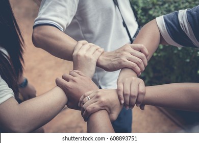 Five arms with hands of girls holding each other joining on white background - Shutterstock ID 608893751